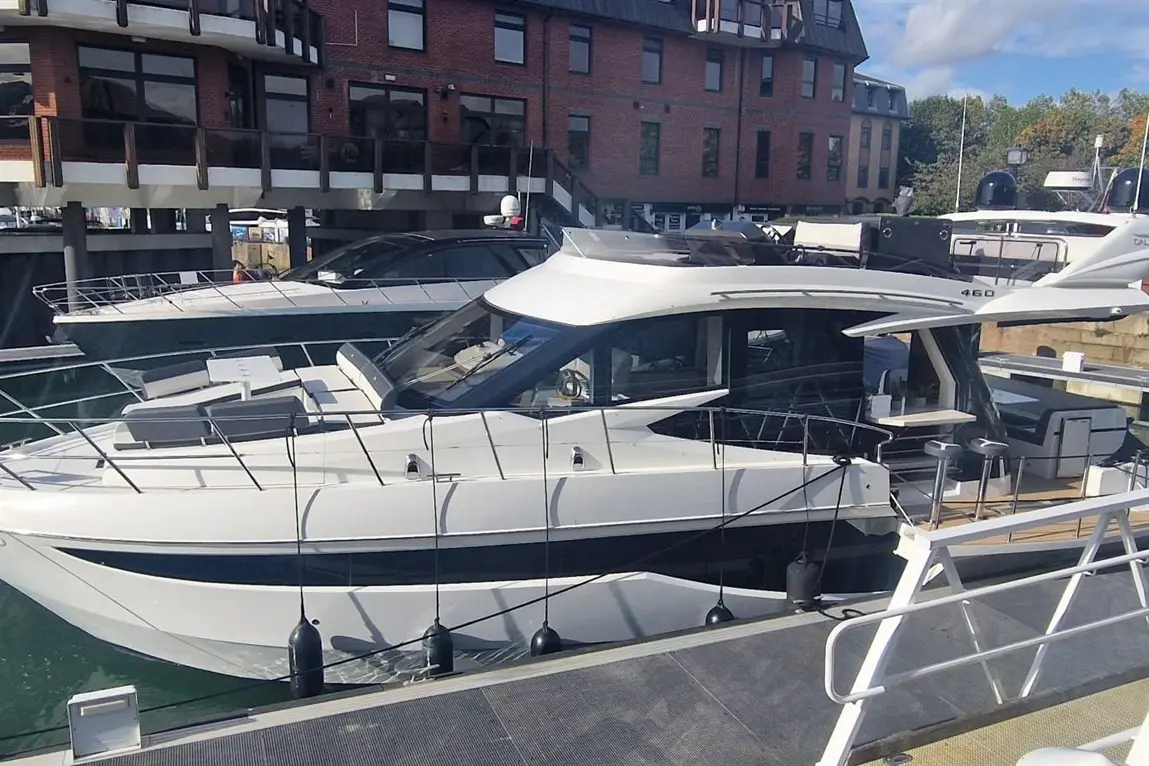 Luxury motor yacht docked at a marina, showcasing a sleek design with a spacious deck and stylish furnishings.